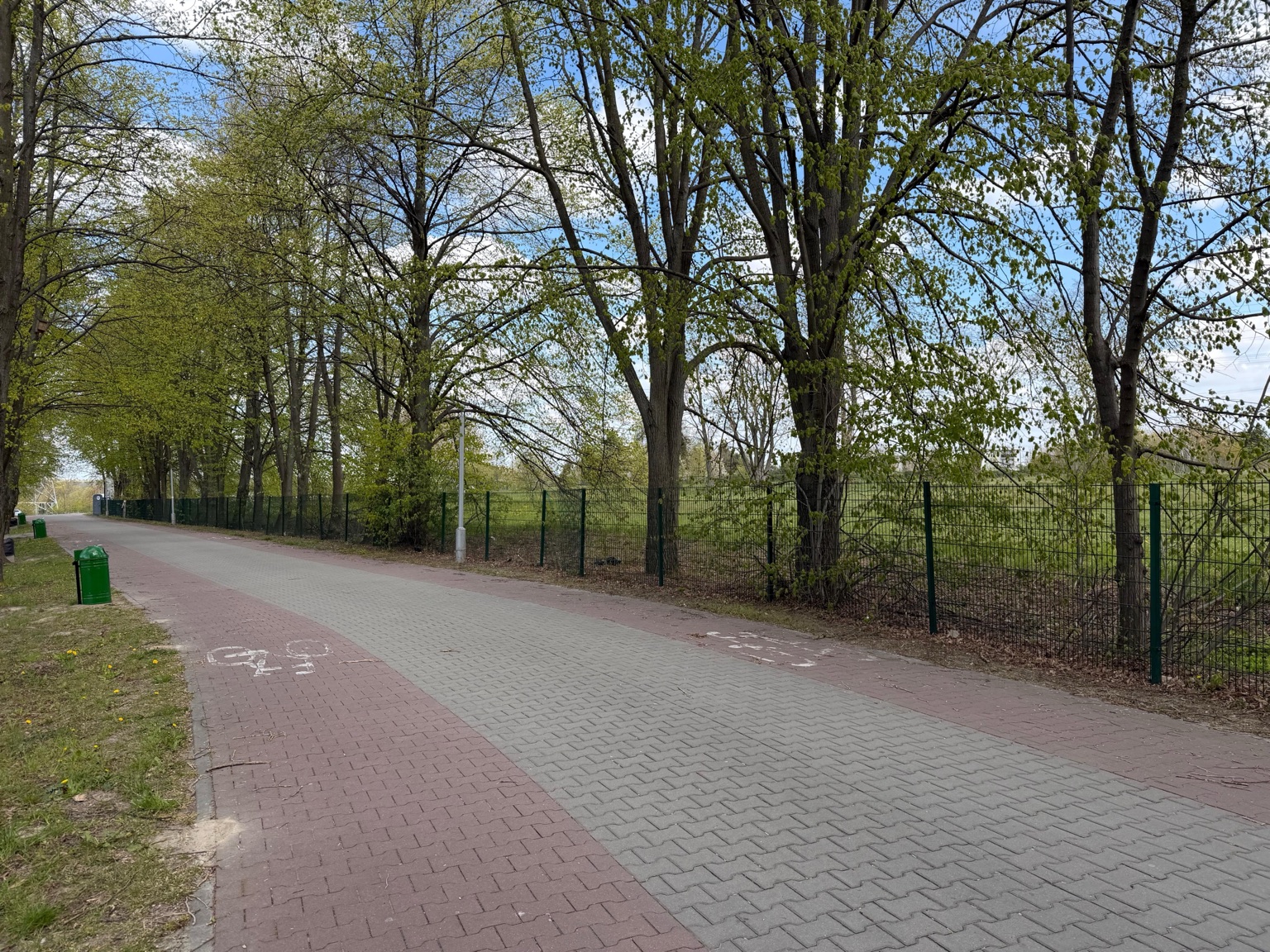 Długi odcinek ścieżki pieszo-rowerowej wzdłuż terenu Akademii Golfa w Lublinie.